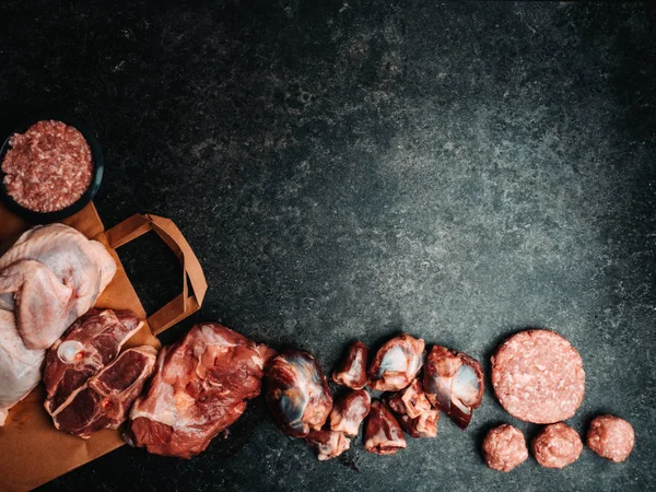 Diferentes tipos de menudillos de carne y pavo en bolsa de papel ecológico, en mesa de hormigón con espacio para copiar — Foto de Stock