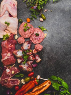 Farklı et türleri. Taze kasap koyu arka planda et çeşitleri kesti. Sebze ve baharat ile dekore edilmiştir. Üst te. Kopyalama alanı