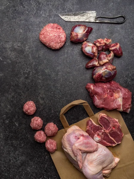 Diferentes tipos de menudillos de carne y pavo en bolsa de papel ecológico, en mesa de hormigón con espacio para copiar —  Fotos de Stock