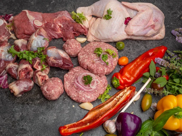 Diferentes tipos de carne crua: carne bovina, frango, cordeiro, gilbert, carne de porco, ervas, alface, alho, tomate cereja, pimentão, verdura — Fotografia de Stock