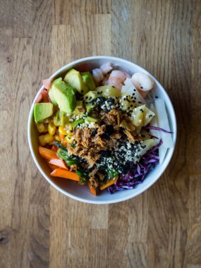 geleneksel Hawaii çanak, deniz ürünleri ile, erişte, tohum, avokado, ananas, soğan, salata, soslar ile, ahşap arka plan üzerinde