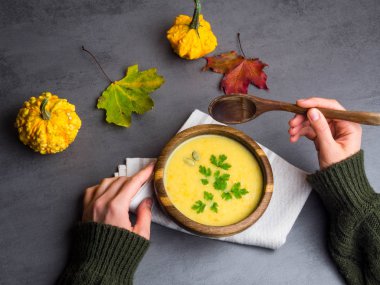 Bayan elleri balkabağı ve kavrulmuş nohut çorbası ile tahta bir kase tutan. Üstte görüntü