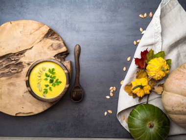 sıcak sarı kabak ve mercimek çorbası, tohumlu, meşe ahşap kase maydanoz, ahşap kaşık, mutfak keten havlu dekoratif sonbahar yaprakları, sağlıklı gıda kavramı