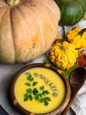 sıcak sarı kabak ve mercimek çorbası, tohumlu, meşe ahşap kase maydanoz, ahşap kaşık, mutfak keten havlu dekoratif sonbahar yaprakları, sağlıklı gıda kavramı