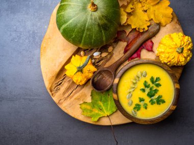 Krema lı kabak, havuç, kabak çekirdeği ile mercimek çorbası, tahta kasede maydanoz, dekoratif kabak ve sonbahar yaprakları