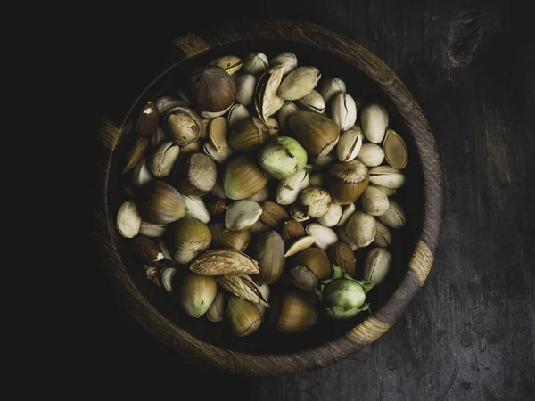 ダークブラウンの木の背景にあるボウルの中のナッツと種 — ストック写真