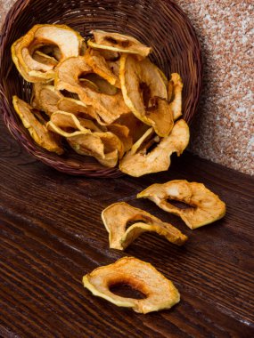 Tahta masadaki hasır sepette kurumuş organik elmalar.