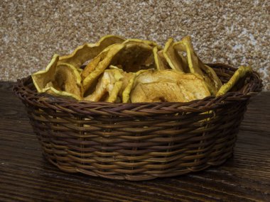 Tahta masadaki hasır sepette kurumuş organik elmalar.