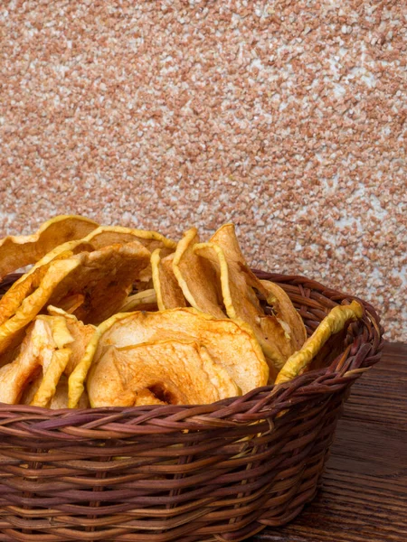 Dried organic apples in a wicker basket on wooden table — Stock Photo, Image