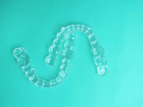 Aligners dentários invisíveis braquetes de dentes modernos, aparelhos transparentes para alisar os dentes em odontologia estética e ortodontia sobre fundo de cor de hortelã — Fotografia de Stock