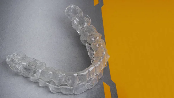 Dentes dentários invisíveis suportes aligners dentes aparelhos de plástico retentores para endireitar os dentes em cinza, fundo laranja — Fotografia de Stock