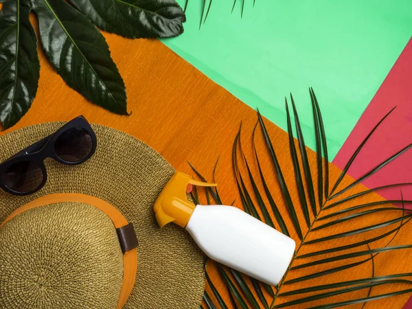 Accesorios del viajero como Sungrassed, sombrero, protector solar, hojas de ramas de palma tropical sobre fondo colorido de moda. Viajes, verano, concepto de vacaciones. Piso tendido, vista superior . — Foto de Stock