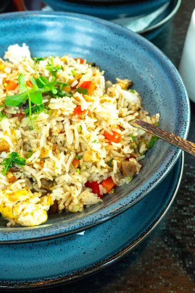 Chinese cuisine, fried rice with egg omelet, mushrooms and vegetables, rice dish of fried rice in vintage ceramic blue bowls, thai menu, selective focus