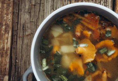 Sonbahar mantarlı ve otlu bir kase çorba, rustik ahşap arka planda yeşil soğan. Vejetaryen Rus mutfağı