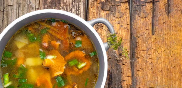 Bowl of soup with autumn chanterelles and herbs, green onion on rusrtic wooden background. Vegetarian Russian cuisine. Banner. Top view, Copy space — Stock Image Bowl Soup Autumn Chanterelles Herbs Green Onion Rusrtic Wooden Background Stock Photo