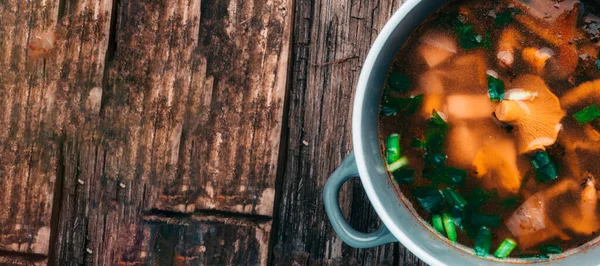 Bowl of soup with autumn chanterelles and herbs, green onion on rusrtic wooden background. Vegetarian Russian cuisine. Banner. Top view, Copy space — Stock Image Bowl Soup Autumn Chanterelles Herbs Green Onion Rusrtic Wooden Background Stock Photo