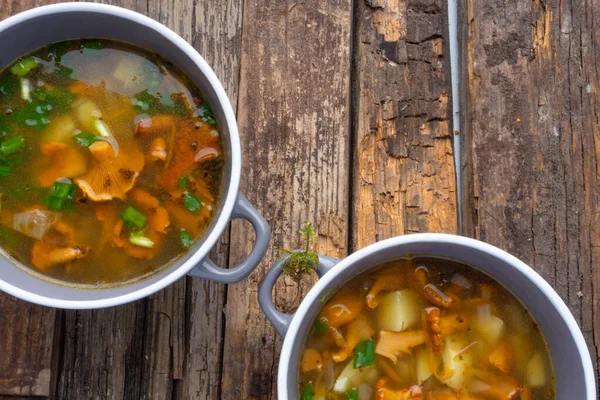 Bowls of soup with autumn chanterelles and herbs, green onion on rusrtic wooden background. Vegetarian Russian cuisine — Stock Image Bowls Soup Autumn Chanterelles Herbs Green Onion Rusrtic Wooden Background Stock Image