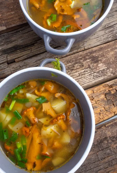 Bowls of soup with autumn chanterelles and herbs, green onion on rusrtic wooden background. Vegetarian Russian cuisine — Stock Image Bowls Soup Autumn Chanterelles Herbs Green Onion Rusrtic Wooden Background Stock Picture