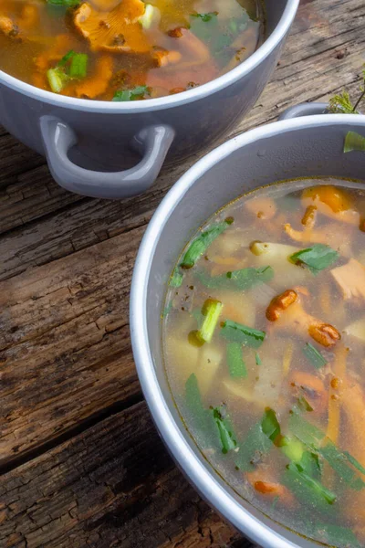 Bowls of soup with autumn chanterelles and herbs, green onion on rusrtic wooden background. Vegetarian Russian cuisine — Stock Image Bowls Soup Autumn Chanterelles Herbs Green Onion Rusrtic Wooden Background Stock Photo