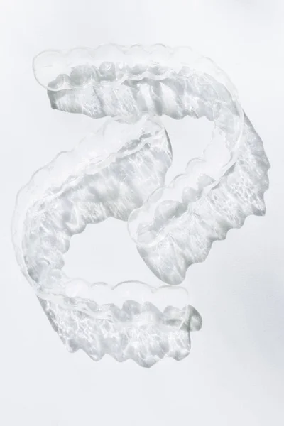 Modern tooth transparent aligners or braces to straighten teeth in cosmetic dentistry and orthodontics with trendy shadows, selective focus