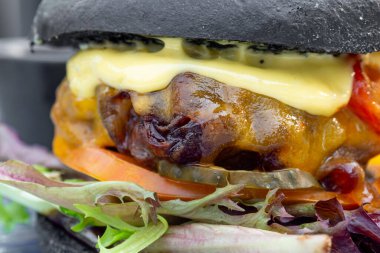 Etli, ekmekli, marullu, peynirli, ketçaplı modern lezzetli siyah burger. Funk yiyecek konsepti. Makro