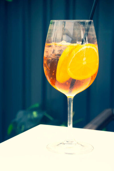 Glass of Alcoholic Aperol Spritz Cocktail with ice cubes and orange slices. Classic Italian trendy cocktail drink. Dark background, selective focus