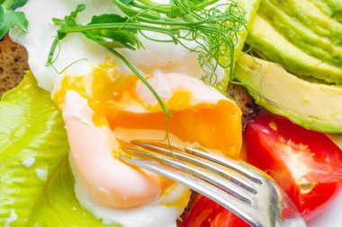 Yumurta, salata, domates ve avokado ile yağda pişirilmiş sağlıklı kahvaltının makro fotoğrafı.