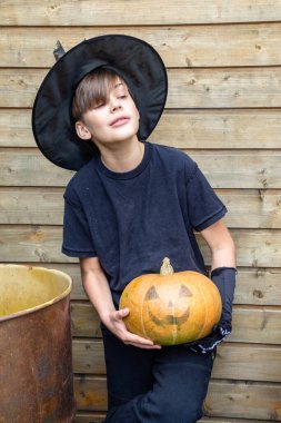 Ahşap arka planda Cadılar Bayramı balkabakları olan mutlu genç çocuk, bayram ve çocukluk konsepti