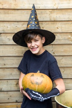 Ahşap arka planda Cadılar Bayramı balkabakları olan mutlu genç çocuk, bayram ve çocukluk konsepti