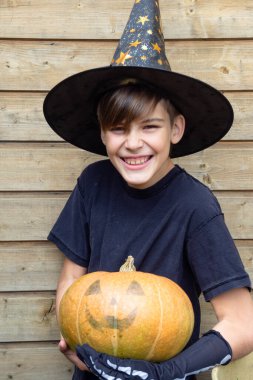 Ahşap arka planda Cadılar Bayramı balkabakları olan mutlu genç çocuk, bayram ve çocukluk konsepti