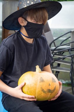Koronavirüs salgınını ve cadılar bayramını karantinaya alın. Karnaval kostümlü çocuk. Korunma maskesi, Coronavirus covid-19 ve tatil konsepti. Tıbbi maske takan çocuk