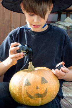 Cadılar bayramı şapkalı çocuk ellerinde balkabağı ve balkabağı, komik zaman, dışarıda Cadılar Bayramı tatili hazırlıkları
