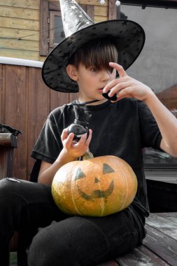 Cadılar bayramı şapkalı çocuk ellerinde balkabağı ve balkabağı, komik zaman, dışarıda Cadılar Bayramı tatili hazırlıkları