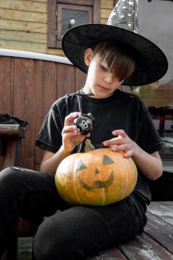 Cadılar bayramı şapkalı çocuk ellerinde balkabağı ve balkabağı, komik zaman, dışarıda Cadılar Bayramı tatili hazırlıkları