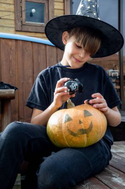 Cadılar bayramı şapkalı çocuk ellerinde balkabağı ve balkabağı, komik zaman, dışarıda Cadılar Bayramı tatili hazırlıkları