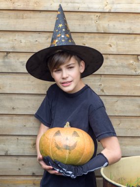 Ahşap arka planda Cadılar Bayramı balkabakları olan mutlu genç çocuk, bayram ve çocukluk konsepti