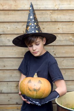 Ahşap arka planda Cadılar Bayramı balkabakları olan mutlu genç çocuk, bayram ve çocukluk konsepti