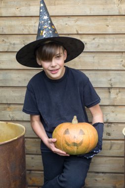 Ahşap arka planda Cadılar Bayramı balkabakları olan mutlu genç çocuk, bayram ve çocukluk konsepti