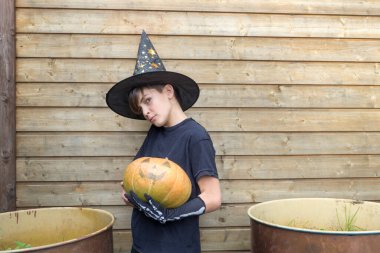 Ahşap arka planda Cadılar Bayramı balkabakları olan mutlu genç çocuk, bayram ve çocukluk konsepti