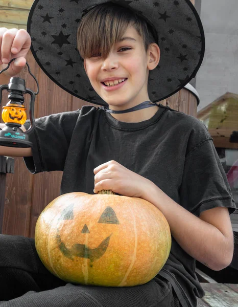 Cadılar Bayramı kostümlü çocuk, şapka ve sonbahar balkabakları ahşap terasta, cadılar bayramı, bayram ve çocukluk konsepti