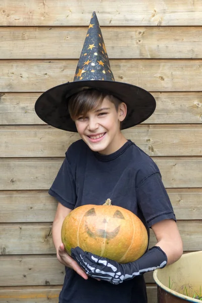 Ahşap arka planda Cadılar Bayramı balkabakları olan mutlu genç çocuk, bayram ve çocukluk konsepti