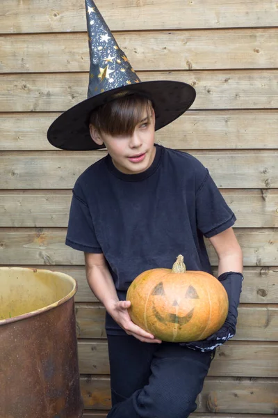 Ahşap arka planda Cadılar Bayramı balkabakları olan mutlu genç çocuk, bayram ve çocukluk konsepti