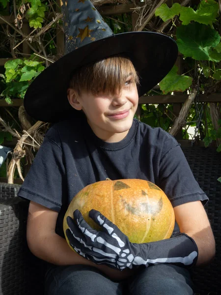 Cadılar Bayramı kostümlü çocuk, şapka ve sonbahar balkabakları açık terasta, cadılar bayramı, tatil ve çocukluk konsepti