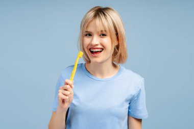 Gülümseyen, sarı saçlı, elinde Amerikan bayrağı olan genç ve güzel bir kadın kameraya bakıyor. Mavi arka planda tek başına duran kadın destekçi. Amerikan bağımsızlık günü konsepti