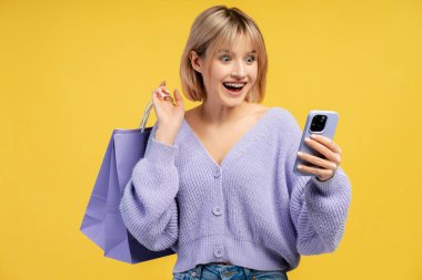 Gülümseyen, sarı saçlı, elinde Amerikan bayrağı olan genç ve güzel bir kadın kameraya bakıyor. Mavi arka planda tek başına duran kadın destekçi. Amerikan bağımsızlık günü konsepti