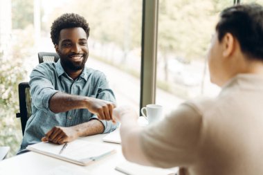 Modern ofislerinde iş anlaşması yaptıktan sonra başarı ve ortaklıklarını kutlamak için birbiriyle yumruk tokuşturan iki mutlu iş adamı. İyi fikir.