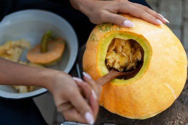 Bir balkabağını ahşap kaşıkla boşaltıp Cadılar Bayramı feneri oymak için hazırlarken ellerinizi yakın tutun.