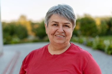 Parkta güneşli bir günün tadını çıkaran neşeli, son sınıf öğrencisi bir kadının portresi aktif yaşlanma ve sağlıklı bir yaşam tarzının vücut bulmuş hali.