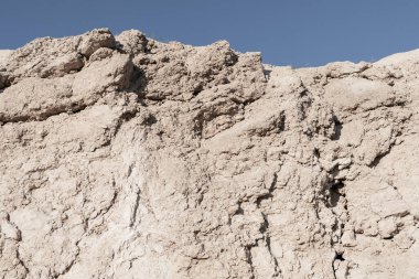 Erimiş kaya yüzeyinin pürüzlü dokusu berrak mavi gökyüzünün altında doğal bir duvar oluşturur.