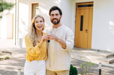 Neşeli ev sahipleri ellerinde anahtarlarla yeni mülklerini kutlarken, banliyödeki başarılı gayrimenkul yatırımlarını da kutluyorlar.